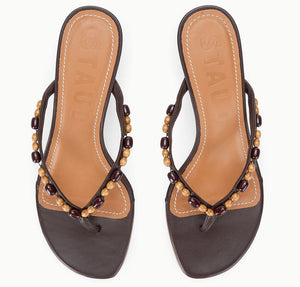 A pair of Staud Freja Thong Kitten Heel sandals in brown leather with tan insoles and decorative wooden beads on the straps, shown from above.