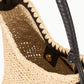 Close-up of the Staud Lani Raffia Bucket Bag with black leather handles and a snap button closure—an essential for effortless, everyday style.