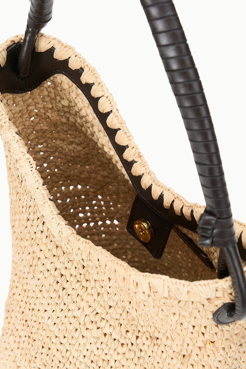 Close-up of the Staud Lani Raffia Bucket Bag with black leather handles and a snap button closure—an essential for effortless, everyday style.