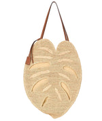 The Staud Large Palm Raffia Bag is a unique woven carryall, shaped like a monstera leaf with brown shoulder straps and tan accents, shown against a white background.