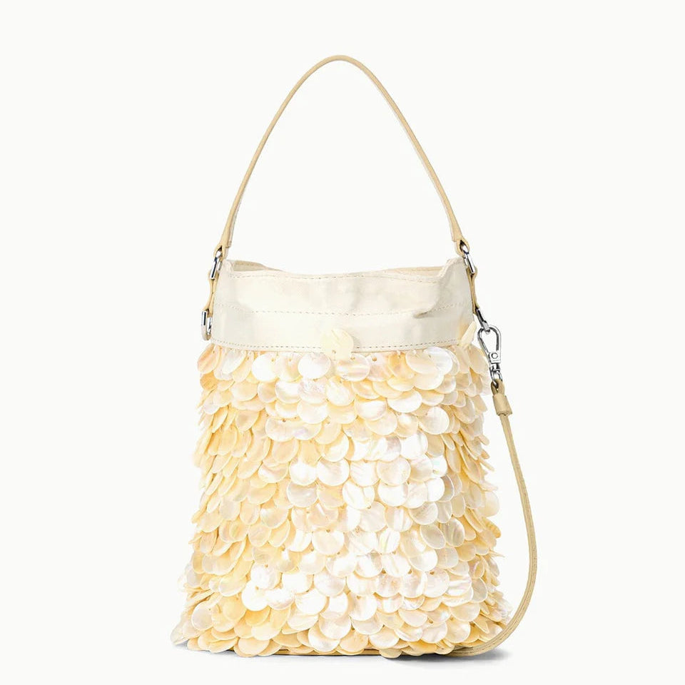 The Staud Lila Mini Bag is a cream-colored bag featuring a top handle, crossbody strap, and overlapping round shell-like accents—a chic accessory for both daytime outings and evening events.