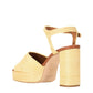 The Staud Jodie Platform Heel is a high-heeled sandal with a chunky block heel, square toe, ankle strap, and woven raffia texture in natural beige.