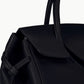Close-up of the Staud Maude Carryall, a black pebbled leather handbag featuring structured handles and a flap closure, shown against a plain white background.