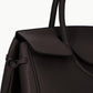 Close-up of the Staud Maude Carryall, a dark brown pebbled leather handbag with a textured surface, featuring a structured handle, organizational pockets, and a distinctive side knot detail.