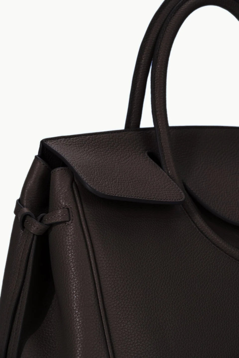 Close-up of the Staud Maude Carryall, a dark brown pebbled leather handbag with a textured surface, featuring a structured handle, organizational pockets, and a distinctive side knot detail.