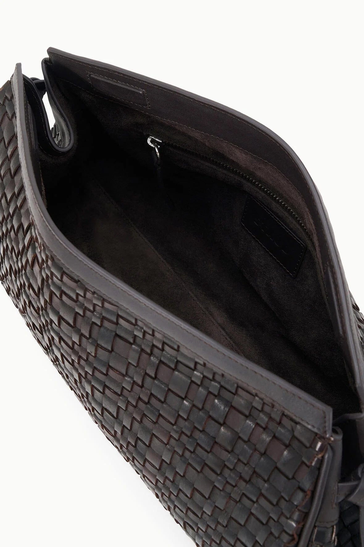 Close-up of the Staud Maude Woven Soft Clutch in dark brown leather, showing its spacious interior with a zippered pocket and a signature knotted tie detail.