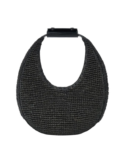 The Staud Moon Raffia Tote Bag is a black woven handbag with a rounded shape, short solid black top handle, and magnetic closure, shown against a white background.