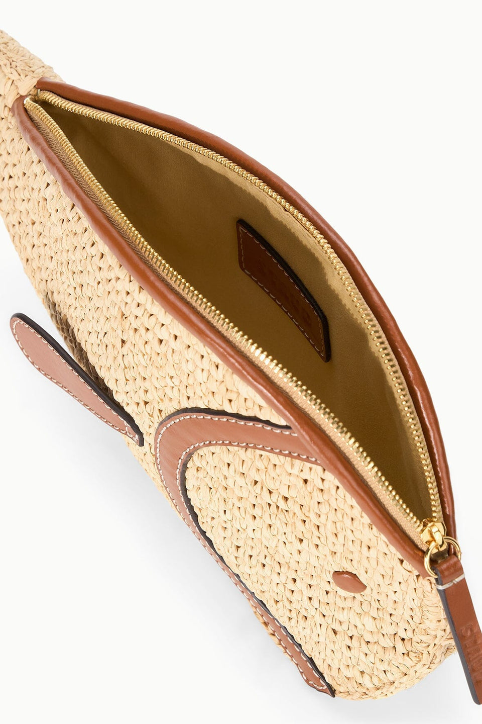 A close-up of the open Staud Pesce Raffia Clutch reveals its empty interior, brown leather trim, zipper closure, and fish-shaped design crafted from natural raffia.