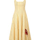 The Staud Wells Monday Stripe Lobster Dress is a sleeveless yellow cotton poplin dress with thin vertical blue stripes, a square neckline, fitted waist, flared skirt, and a red lobster detail near the hem.