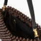 A close-up of the Staud Timmy Convertible Shoulder Bag featuring a brown beaded exterior, black leather strap, gold hardware, and an interior zip pocket.