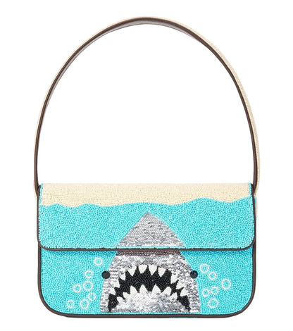 The Staud Tommy Beaded Bag is a rectangular, hand-beaded vegan leather bag with a sequin shark's open mouth in blue water, single strap, and magnetic snap closure.