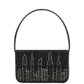 The Staud Tommy Beaded Bag is a black vegan leather handbag with a hand-beaded city skyline, gold and silver accents, a single shoulder strap, and a secure magnetic snap closure.