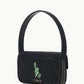 A compact black Tommy Beaded Bag by Staud, made from vegan leather with a textured finish, features an embroidered Statue of Liberty outline and the “STAUD” logo on the front flap, secured with a magnetic snap closure.