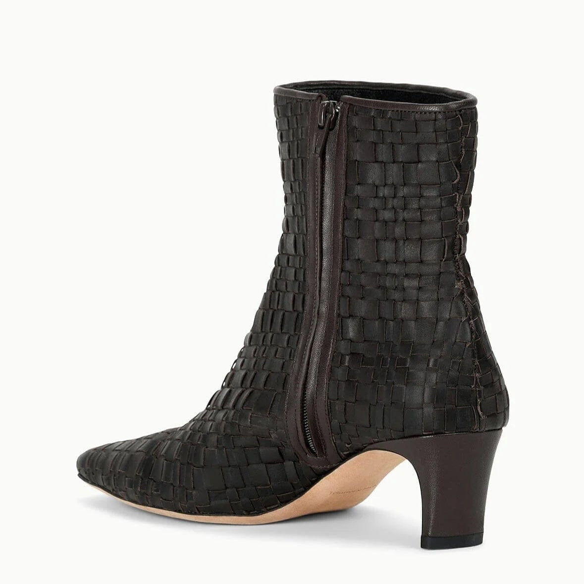 The Staud Wally Woven Leather Ankle Boot features black woven leather, a pointed toe, mid-height blade heel, and side zipper, shown against a light background.
