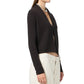 A woman wears the Stealth Cardigan by Guest in Residence, a lightweight open-front style in black, paired with off-white high-waisted pants, shown from the side against a white background.