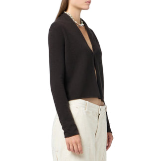 A woman wears the Stealth Cardigan by Guest in Residence, a lightweight open-front style in black, paired with off-white high-waisted pants, shown from the side against a white background.