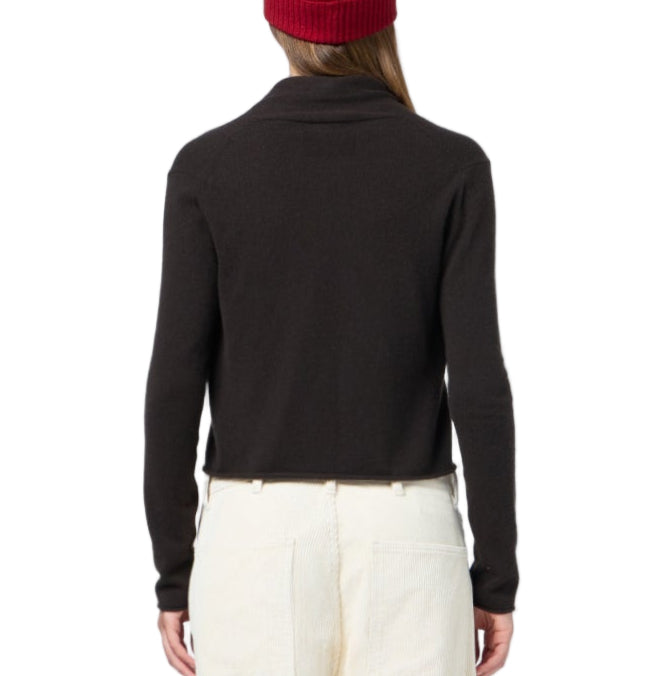 Model wears the Guest in Residence Stealth Cardigan over a black long-sleeve top, paired with white pants and a red beanie, shown from the back against a white background.