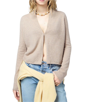A person wearing the Guest in Residence Stealth Cardigan in beige, blue jeans, a yellow sweater tied at the waist, and a shell necklace.