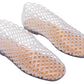 The Steve Madden Kids Girls’ Grovee Jelly Flat is a pair of translucent, lattice-patterned plastic shoes with closed toes and flat soles. These lightweight slip-on shoes are designed for easy wear and are displayed on a white background.