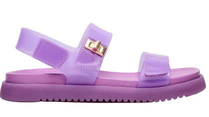 Introducing the Girls’ Jelly Mona Sandal by Steve Madden Kids—a stylish purple sandal featuring a trendy flatform design, adjustable straps, and a chic gold buckle detail on the side, perfect for your little fashionista.