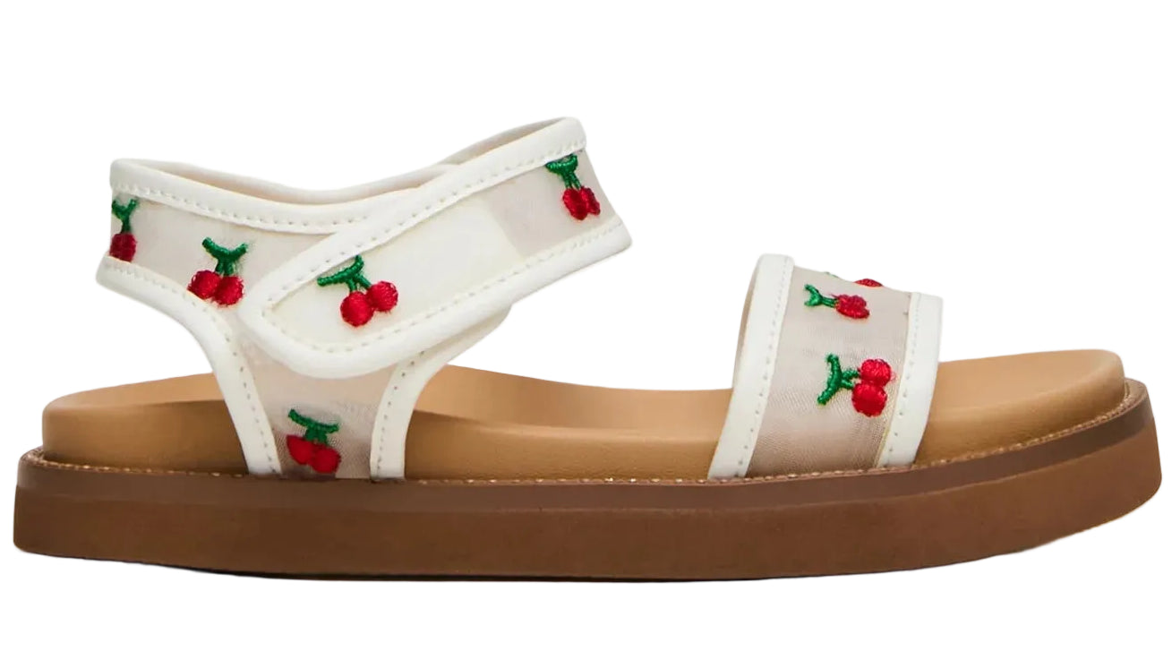 The Toddlers’ Lyla Sandal by Steve Madden Kids features a white footbed with a brown sole and embroidered cherries and green leaves on the straps, while adjustable Velcro straps ensure a comfortable fit.