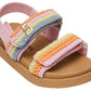 The Toddlers’ Mona Sandal by Steve Madden Kids features a tan sole, pink footbed, and pastel rainbow crochet straps, complete with a small gold buckle and hook-and-loop closures for easy wear.