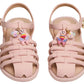 A pair of Steve Madden Kids Toddlers’ Pocket Charmed Sandals in pink, featuring strappy ankle straps and adorned with a butterfly charm and a smiley face charm filled with small colorful beads on each shoe.
