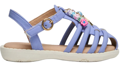 The Steve Madden Kids Toddlers’ Pocket Charmed Sandal features a light purple strappy design with a white sole, gold buckle, and colorful bead charms spelling “LOVE,” plus a pink flower detail on the top strap.