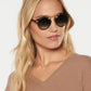 A woman with long blonde hair wears Krewe STL II sunglasses and a tan oversized V-neck sweater, standing against a plain light background.