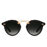 The Krewe STL Nylon Polarized Sunglasses feature an oversized round black frame with gold accents and dark gradient flat nylon lenses, shown on a white background.