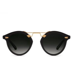 The Krewe STL Nylon Polarized Sunglasses feature an oversized round black frame with gold accents and dark gradient flat nylon lenses, shown on a white background.