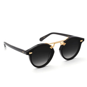 The Krewe STL Nylon Polarized Sunglasses feature a black oversized round frame, flat nylon polarized lenses, and a gold metal bridge. Classic dark lens style displayed on a white background.
