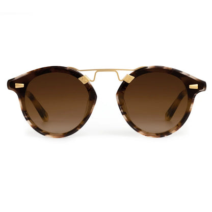 Krewe STL Nylon Sunglasses feature a round, oversized tortoiseshell-patterned frame, brown gradient flat nylon lenses, and gold metal accents on the bridge, shown from the front.