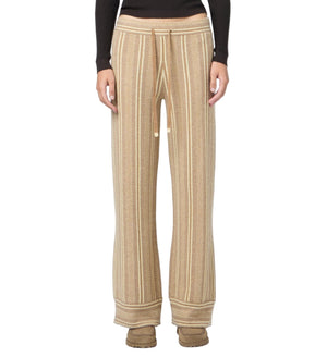 A person models the Guest in Residence Stripe Lounge Pant, featuring beige and cream stripes, paired with a black long-sleeve top; photo shows them from the waist down.
