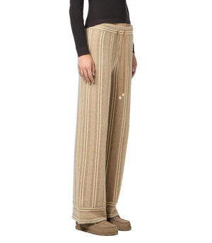 A person wearing the Guest in Residence Stripe Lounge Pant, a dark long-sleeve top, and beige shoes stands against a white background.