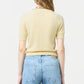 A person with long, wavy hair is shown from the back, wearing a light yellow Guest in Residence Sweater Tee and light blue jeans against a plain background.