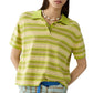 A woman wears the Guest in Residence Short Sleeve Stripe Rugby over a cotton-cashmere tee for a layered look, accessorized with a beaded necklace, hand in pocket, and blue-striped pants.