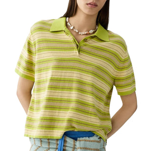 A woman wears the Guest in Residence Short Sleeve Stripe Rugby over a cotton-cashmere tee for a layered look, accessorized with a beaded necklace, hand in pocket, and blue-striped pants.