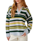 A woman wearing the Sablyn Billie Sweater—a long-sleeve, collared cashmere top with horizontal stripes in green, yellow, pink, and white—paired with off-white pants.