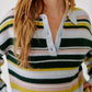 A woman with long, wavy hair wears the Sablyn Billie Sweater, featuring a collared design and horizontal stripes in green, white, pink, yellow, and blue. She stands against a plain white background.