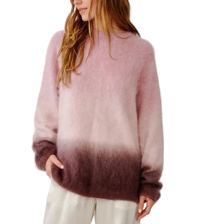 A woman models the Sablyn June Ombre Crewneck Sweater, a fuzzy long-sleeve piece featuring pink and purple tones in a classic raglan silhouette. She pairs it with light-colored pants, her upper body visible as she turns her head to the side.