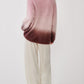 A person is seen from behind wearing the Sablyn June Ombre Crewneck Sweater, featuring a fuzzy pink and burgundy ombré finish, paired with loose white pants against a plain white background.