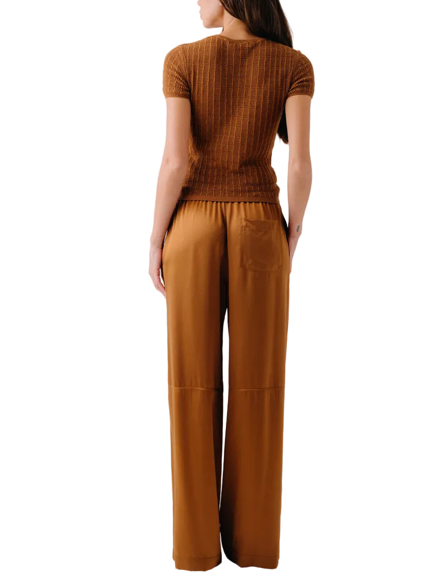 A woman is seen from behind, wearing a short-sleeved brown ribbed top and Sablyn’s Lexi Lower Rise Relaxed Pull On Pant.