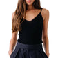 Model wearing the Sablyn Ada V-Neck Cami with Lace, styled with high-waisted dark pleated pants, hands in pockets; shown from shoulders to hips.