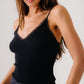 A woman wears the Sablyn Ada V-Neck Cami with Lace, a black ribbed wool top, standing against a plain light background.