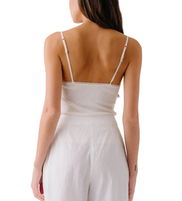 A woman is seen from the back wearing the Ada V-Neck Cami with Lace by Sablyn and high-waisted white pants against a plain background.