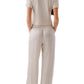 A woman stands with her back to the camera, wearing the Sablyn Charleston Relaxed Crewneck Tee in beige, paired with matching wide-leg pants featuring an elastic waistband.
