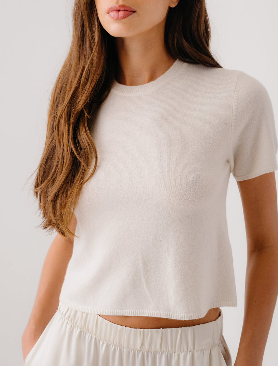 A woman wears the Sablyn Charleston Relaxed Crewneck Tee with light-colored pants, standing against a plain background.