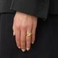 A hand wearing the Lie Studio Sandra Ring on the index finger, its sleek gold band adding elegance to a black suit.