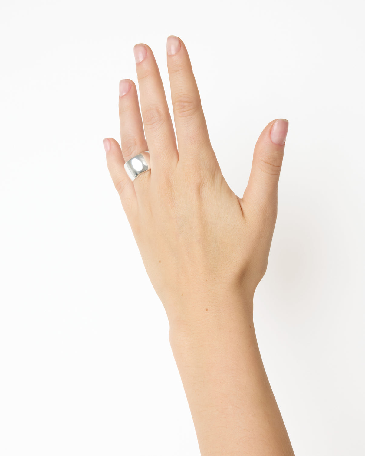 A left hand with natural nails wears the Lie Studio Sandra Ring, a wide sterling silver band on the middle finger, set against a plain white background.
